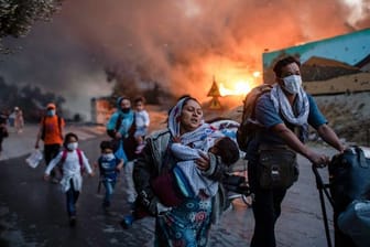Migranten fliehen vor einem großen Feuer mit ihren Habseligkeiten aus dem Flüchtlingslager Moria.