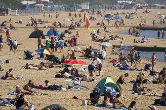 Zahlreiche Menschen genießen das warme Wetter am Strand von Bournemouth.