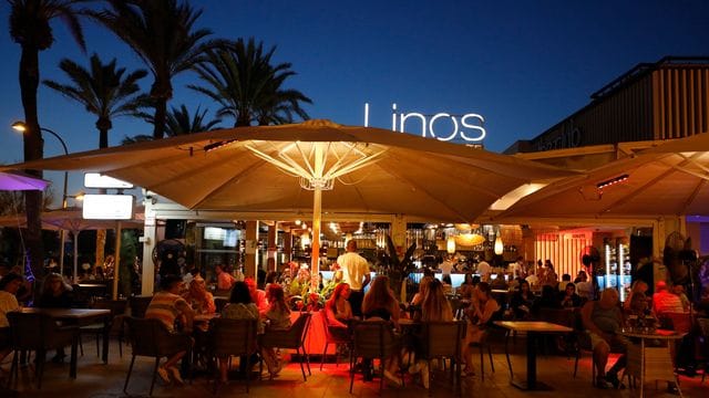 Menschen sitzen in einer Bar an der Strandpromenade von Palma.