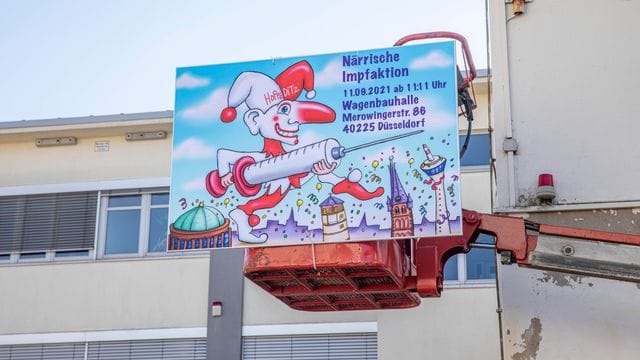 "Närrische Impfaktion" steht auf einem Schild an der Wagenbauhalle in Düsseldorf. "Närrische Impfaktion" steht auf einem Schild an der Wagenbauhalle in Düsseldorf.