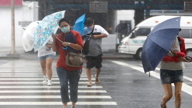 Menschen mit Regenschirmen kämpfen in Keelung gegen das Unwetter. Menschen mit Regenschirmen kämpfen in Keelung gegen das Unwetter.