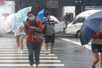 Menschen mit Regenschirmen kämpfen in Keelung gegen das Unwetter.