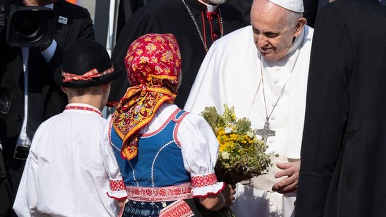 Papst Franziskus wird von zwei Kindern in traditioneller Kleidung am Flughafen im slowakischen Bratislava empfangen.