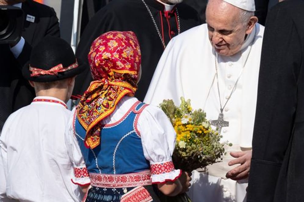 Papst Franziskus wird von zwei Kindern in traditioneller Kleidung am Flughafen im slowakischen Bratislava empfangen.