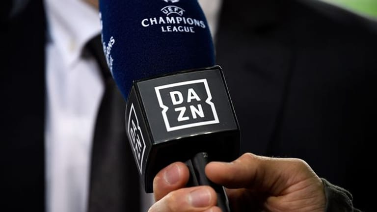 Ein Reporter hält ein Mikrofon des Streamingdienstes DAZN während eines Interviews fest.