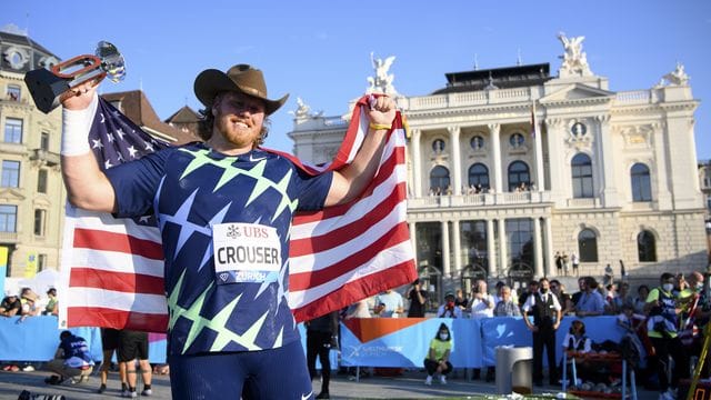 Ryan Crouser aus den USA hält seine Siegertrophäe in der Hand und feiert den ersten Platz.