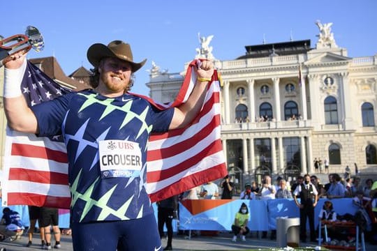 Ryan Crouser aus den USA hält seine Siegertrophäe in der Hand und feiert den ersten Platz.