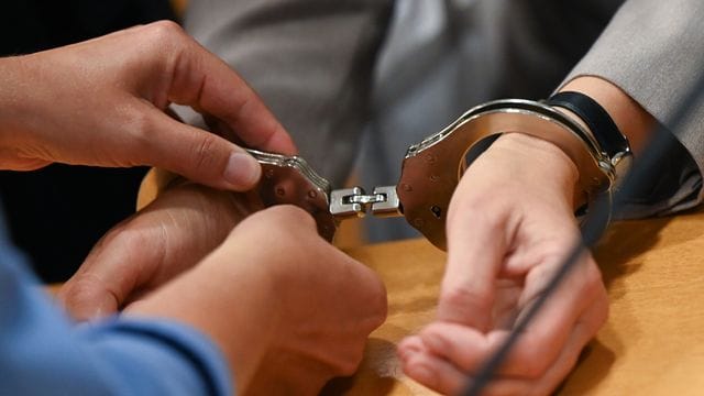 Eine Justizbeamtin nimmt der Angeklagten im Gerichtssaal des Landgerichts Hanau die Handschellen ab. Eine Justizbeamtin nimmt der Angeklagten im Gerichtssaal des Landgerichts Hanau die Handschellen ab.