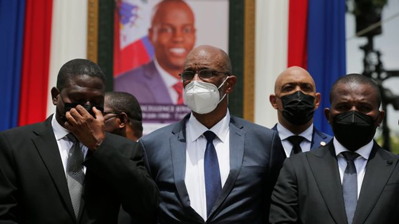 Ariel Henry (M), designierter Premierminister von Haiti, und Interims-Regierungschef Claude Joseph (r) stehen vor einem Porträt des ermordeten haitianischen Präsidenten Jovenel Moise.