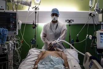 Ein medizinischer Angestellter (M) kümmert sich auf der Intensivstation eines Krankenhauses in Pierre-Benite um einen Corona-Patienten.