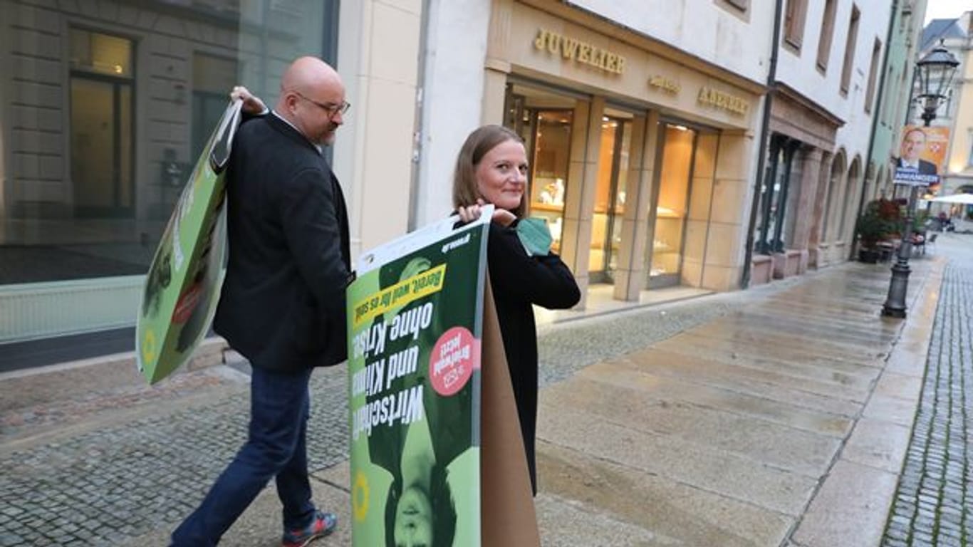 Wolfgang Wetzel, (l) Spitzenkandidat der Grünen und Christin Furtenbacher, Landesvorstandssprecherin der Grünen in Sachsen, laufen mit Wahlplakaten durch die Innenstadt von Zwickau.