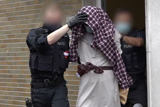Ein Mann wird im Zusammenhang mit dem mutmaßlich geplanten Anschlag von Polizisten abgeführt.