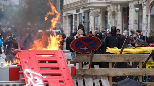 Maskierte Demo-Teilnehmer stehen hinter einer Barrikade. Maskierte Demo-Teilnehmer stehen hinter einer Barrikade.