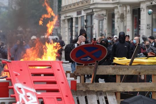 Maskierte Demo-Teilnehmer stehen hinter einer Barrikade.