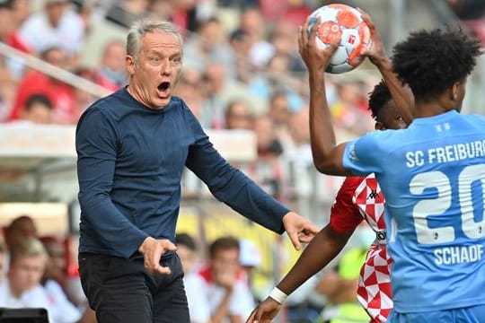 Freiburgs Trainer Christian Streich (l) recht sich bei einer Szene im Spiel beim FSV Mainz auf.