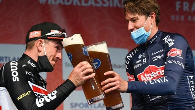 John Degenkolb (l) stößt mit Eschborn-Frankfurt-Sieger Jasper Philipsen an.