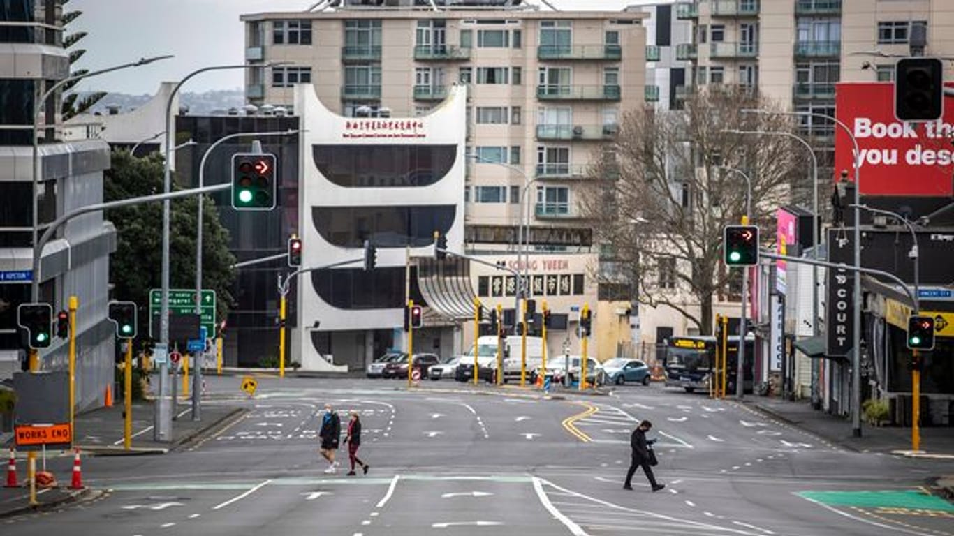 Menschen überqueren im zentralen Geschäftsviertel in Auckland fast leere Straßen.