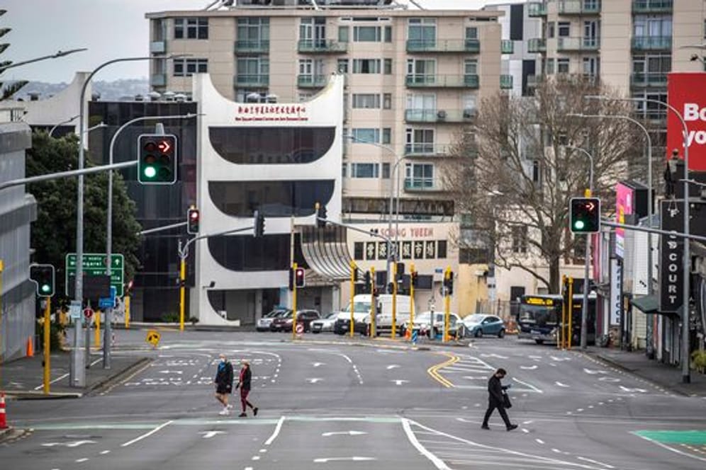 Menschen überqueren im zentralen Geschäftsviertel in Auckland fast leere Straßen.