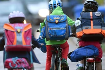 Kinder sind auf einer Straße mit dem Fahrrad unterwegs zur Schule.
