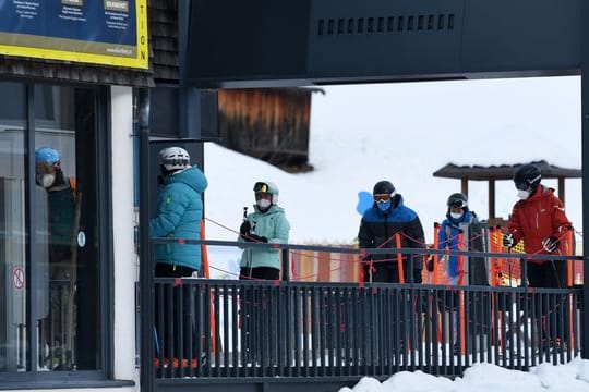 Wintersportler stehen in Tirol mit Mund-Nasen-Schutz an einem Skilift an.