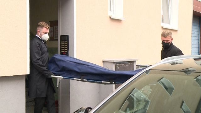 Bestatter bringen das Opfer zu ihrem Fahrzeug.
