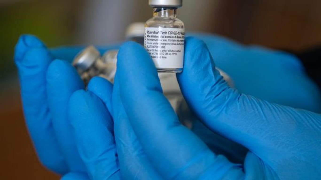Ein Impfarzt hält einen Behälter mit dem Impfstoff gegen Covid-19 von Pfizer in einem Impfzentrum während der Impfung.