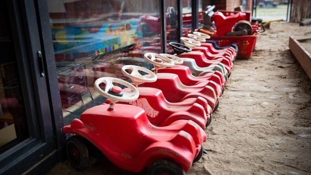 Mehrere Bobbycars stehen auf dem Spielplatz eines Kindergartens.