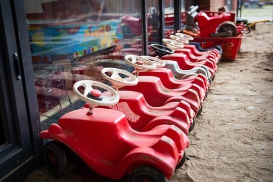 Mehrere Bobbycars stehen auf dem Spielplatz eines Kindergartens.