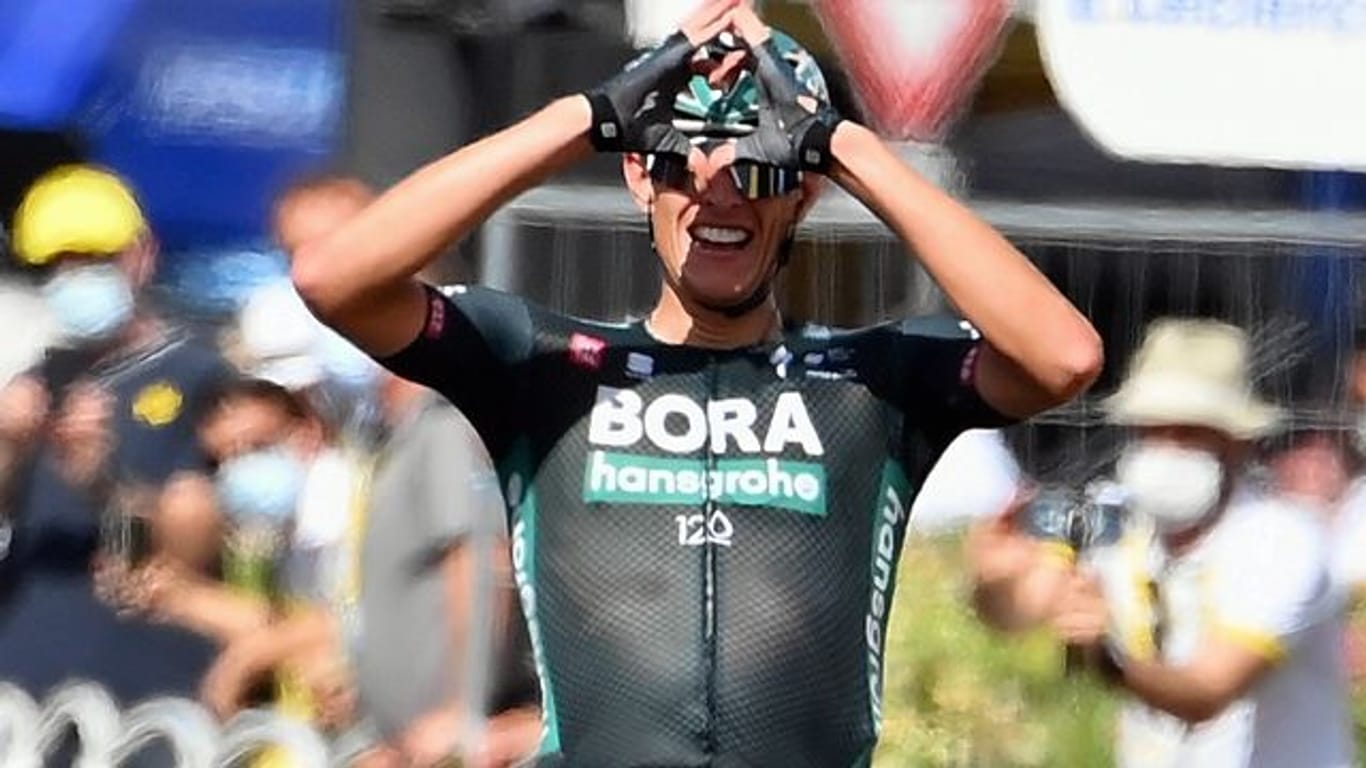 Nils Politt formt nach seinem Tagessieg bei der Tour de France mit den Händen im Ziel ein Herz.