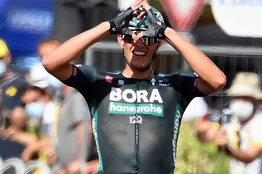 Nils Politt formt nach seinem Tagessieg bei der Tour de France mit den Händen im Ziel ein Herz.