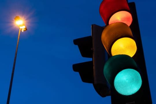 Eine Ampel zeigt am frühen Morgen die Farben rot, gelb und grün.