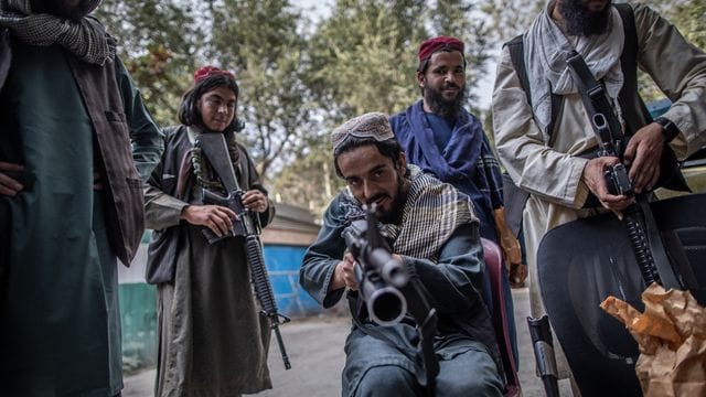 Ein junger Taliban-Kämpfer zielt zum Spaß mit seinem Gewehr in Richtung Fotograf, während er vor einer Polizeistation in Kabul Wache hält.