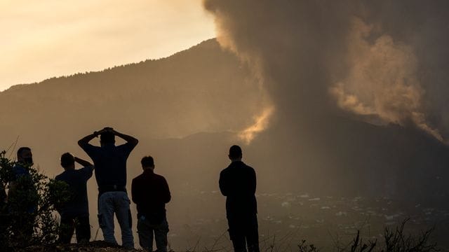 Anwohner blicken von einem Hügel aus auf die Lava, die weiterhin aus dem Vulkan auf der Insel La Palma fließt. Anwohner blicken von einem Hügel aus auf die Lava, die weiterhin aus dem Vulkan auf der Insel La Palma fließt.