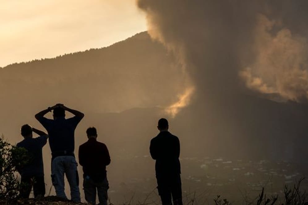 Anwohner blicken von einem Hügel aus auf die Lava, die weiterhin aus dem Vulkan auf der Insel La Palma fließt.