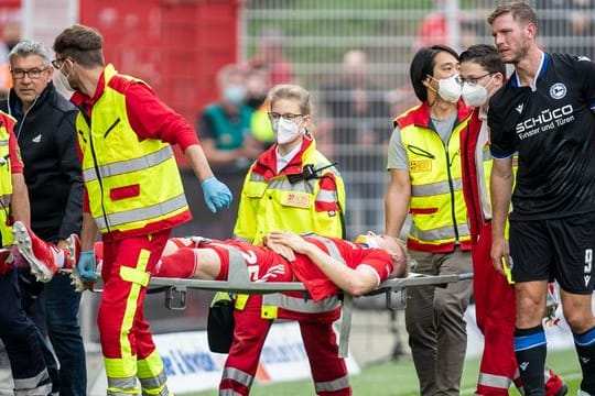 Berlins Timo Baumgartl wird nach einem Zusammenstoß mit Bielefelds Fabian Klos (r) vom Spielfeld getragen.