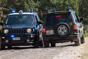 Zwei Polizeifahrzeuge auf einem Waldweg in Sizilien (Archivbild). Eine Großfahndung nach einem Mafiaboss wurde am Freitag erfolglos abgebrochen.