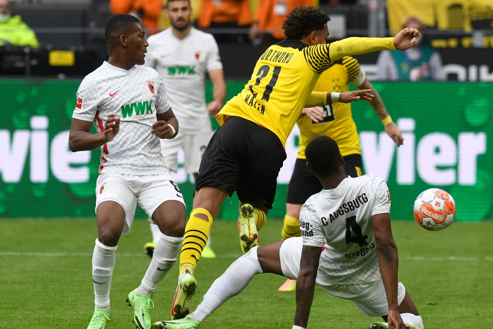 Stellvertertend für eine intensive Partie: Die Augsburger Reece Oxford (r.) und Carlos Gruezo (l). nehmen Dortmunds Donyell Malen (M.) in die Zange.