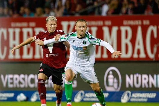 Hannovers Tom Trybull (r) schirmt den Ball vor dem Nürnberger Lino Tempelmann (l) ab.