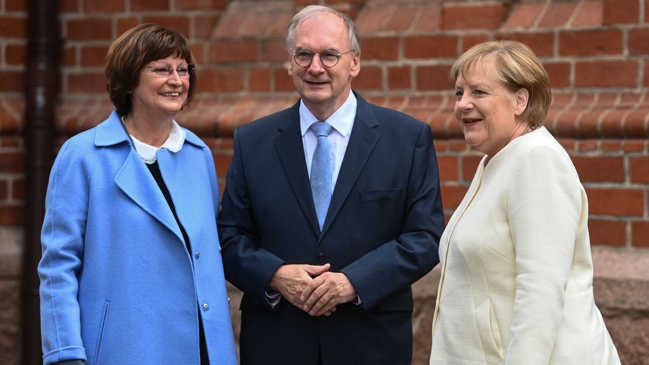 Reiner Haseloff (CDU), Ministerpräsident von Sachsen-Anhalt, und seine Frau Gabriele (l) begrüßen Bundeskanzlerin Angela Merkel (CDU) vor Beginn eines ökumenischen Gottesdienstes an der Pauluskirche in Halle/Saale.