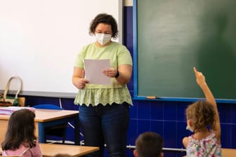 Eine Lehrerin steht vor einer Schulklasse (Symbolbild): An Schulen entfällt die Maskenpflicht für Kinder bis zur sechsten Klasse.