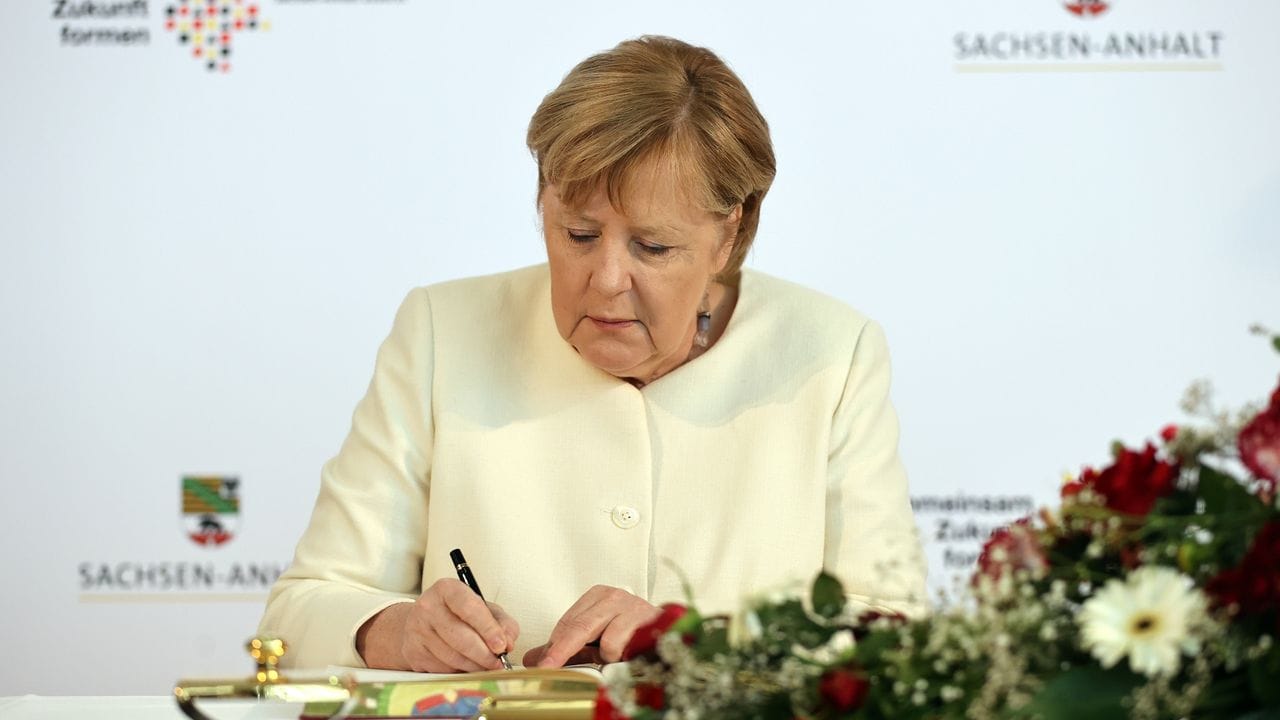 Angela Merkel trägt sich vor Beginn des Festakts in das Goldene Buch der Stadt Halle ein.