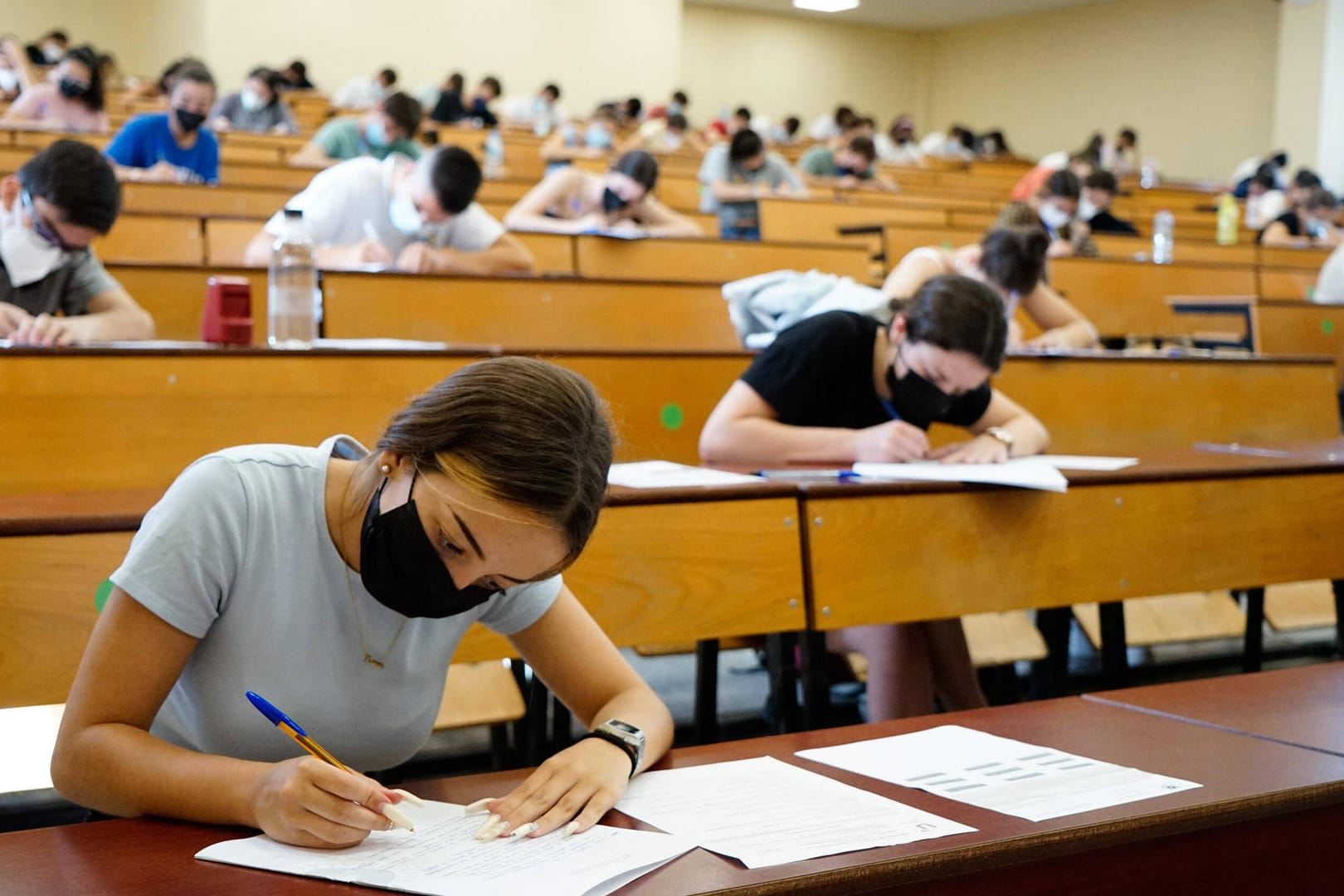 Studentinnen und Studenten sitzen mit Masken und Abstand in einem Hörsaal (Archivbild): In Bayern startet das Semester mit Präsenzveranstaltungen – Schwangere werden an manchen Hochschulen aber davon ausgeschlossen.