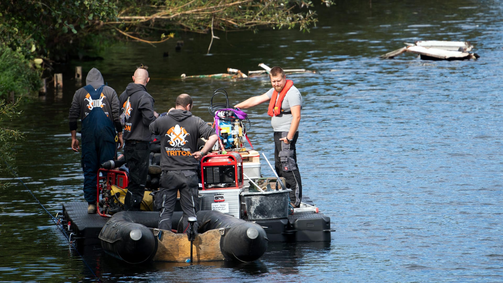 Mitarbeiter eines Bergungsunternehmens transportieren auf einem Ponton Ausrüstung: Die Bergung des bei der Hochwasserkatastrophe in der Ruhr gesunkenen Fahrgastschiffes "Moornixe" beginnt.