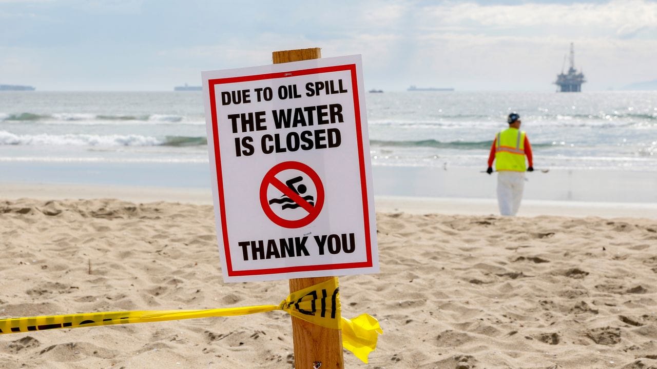 Ein Warnschild in Huntington Beach, im Hintergrund eine Ölplattform.