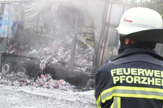 Ein Feuerwehrmann steht vor dem ausgebrannten Sattelauflieger eines Lastwagens auf der Autobahn 8 zwischen Karlsruhe und Stuttgart: Hier sorgt am Dienstagmorgen ein Lkw-Fahrer für Verzögerungen.
