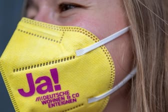 Eine Unterstützerin der Initiative "Deutsche Wohnen & Co. enteignen" trägt eine Maske mit einem deutlichen Bekenntnis zur Enteignung.