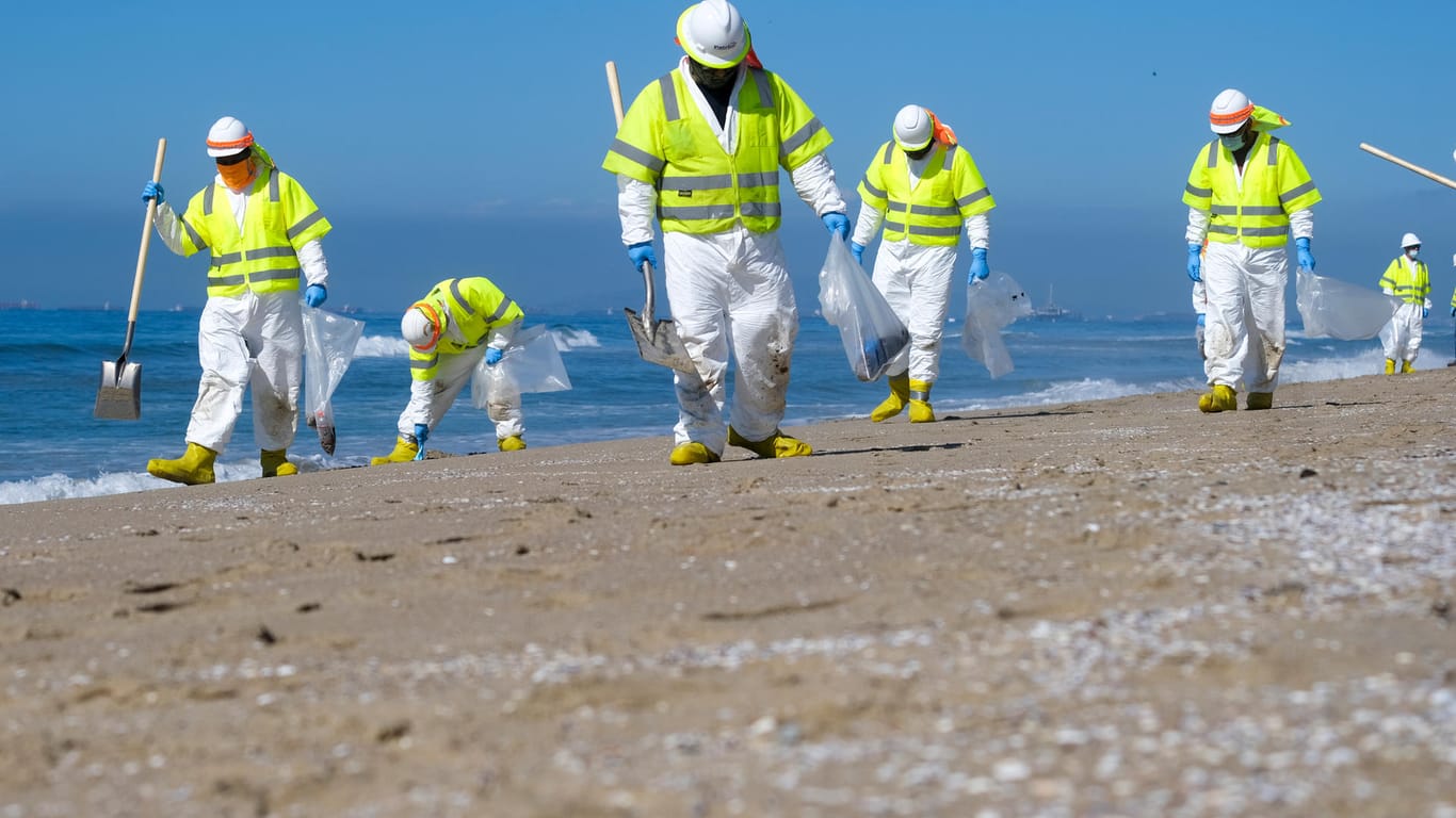 USA, Huntington Beach: Arbeiter in Schutzanzügen säubern den verunreinigten Strand nach einem Ölaustritt.