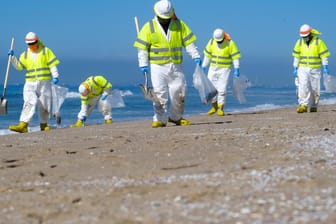 USA, Huntington Beach: Arbeiter in Schutzanzügen säubern den verunreinigten Strand nach einem Ölaustritt.