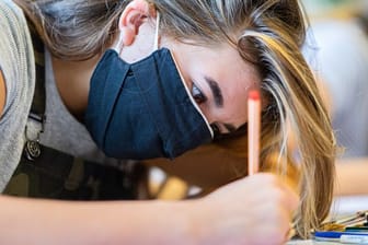 Eine Schülerin einer Gesamtschule sitzt mit einer Mund- und Nasenmaske an ihrem Tisch (Symbolbild): Ab 2. November sollen Schüler in ganz NRW die Maske abnehmen dürfen.