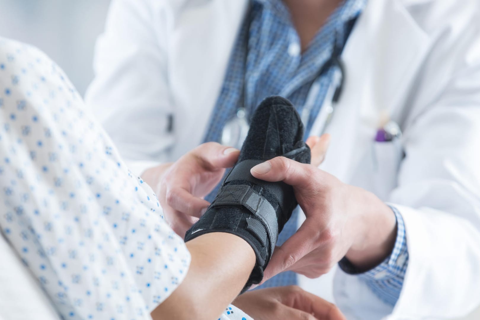 Patientin mit Armmanschette im Gespräch mit einem Arzt. Rheumatisch bedingte Gelenkschmerzen können sehr schmerzhaft sein. Manchmal bringt nur eine Operation Linderung.